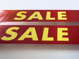 The word sale in English printed big yellow letters on a red background. The concept of seasonal sales