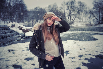 Model posing girl posing against a background of winter nature. Dressed for winter beautiful appearance, long hair