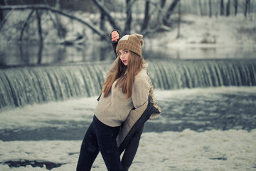 Model posing girl posing against a background of winter nature. Dressed for winter beautiful appearance, long hair