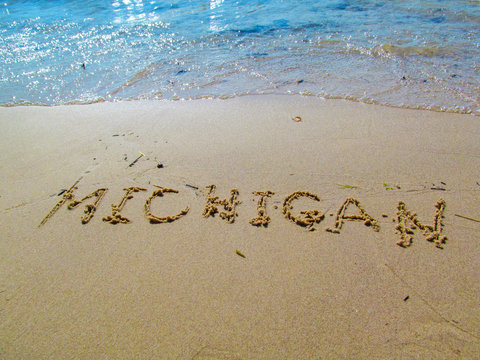 Hand drawn word on sandy beach at Lake Michigan.
Close up detailed image of sand, text and lake water.