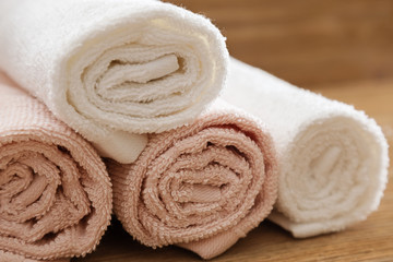Obraz na płótnie Canvas Folded bath towels pink and white colored on wooden table for hotel spa. Clean fluffy towels. Close up.