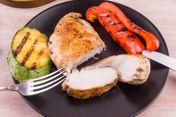 Fried chicken fillet with vegetables on a black plate close-up, macro