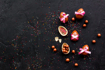 Chocolate Easter eggs as little gift. Black background top view copy space