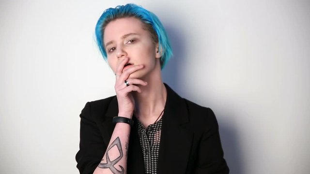 modern youth. unusual girl with blue hair and tattoos posing in front of camera.