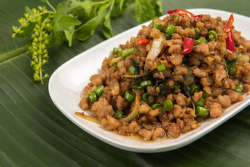 stir fried pork with basil  in white dish on banana leaf