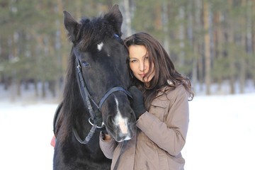 Obraz premium Portrait of a young black hair woman hugging a horse