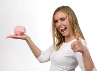 Hübsche blonde Frau begeistert mit Sparschwein in ihrer Hand  und Daumen hoch