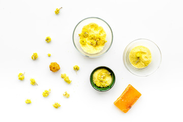 Aromatic spa salt. Yellow spa salt with delicate spring flowers on white background top view