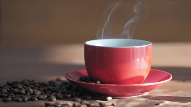 red cup of coffe with steam on wooden table