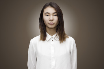 Indoor portait of young attractive asian woman with neutral face dressed in white formal shirt. Emotions, feelings, lifestyle concept