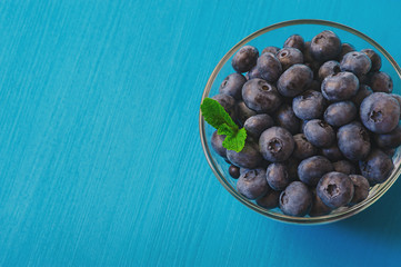 Tasty blueberries with mint on blue background. Blueberries are antioxidant organic superfood.