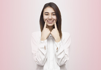 Portrait of young beautiful woman making wide smile with two fingers. Perfect teeth, dental care concept. Emotions, face expressions, lifestyle concept