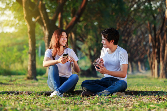 couple using mobile phone and talking in park
