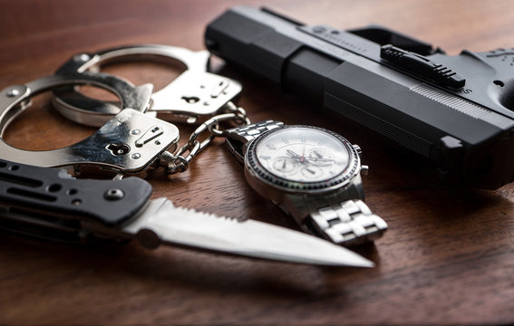 Tactical gear set of Pistol gun knift handcuff and clock on wooden background. Police or military equipment concept.