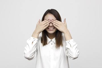 Closeup portrait young, coy woman closing eyes with hands can't see and hiding mouth wide open, isolated white background. See no evil concept. Negative emotion facial expression feelings