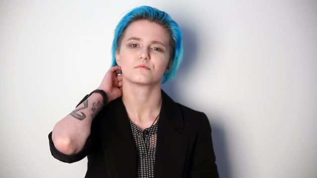 modern youth. unusual girl with blue hair and tattoos posing in front of camera.