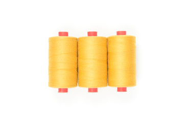 Yellow thread coils on white background, sewing and tailoring supplies