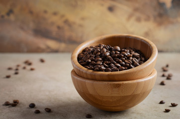 Roasted coffee beans in a wooden bowl on concrete background, selective focus, copy space.