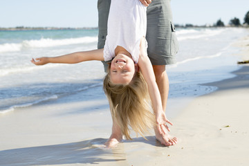father holding sweet young and lovely blond small daughter by her feet playing having fun on the...
