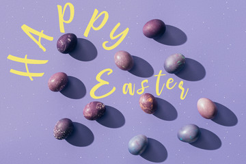 painted eggs on purple background with Happy Easter lettering