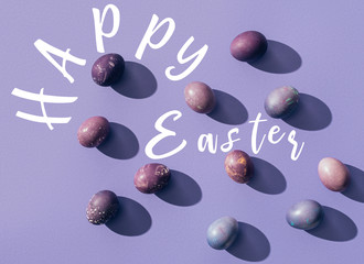 painted chicken eggs on purple background with Happy Easter lettering