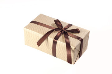 Gift box or present wrapped in brown craft paper and decorated satin ribbon knotted on a bow isolated on white background