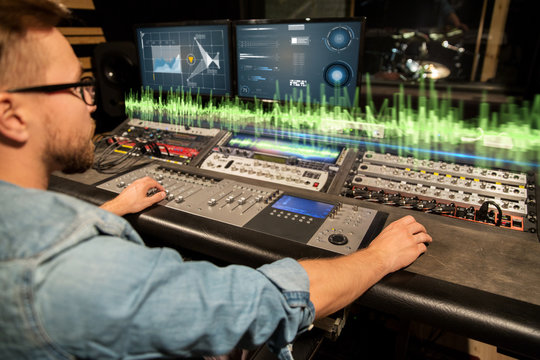man at mixing console in music recording studio