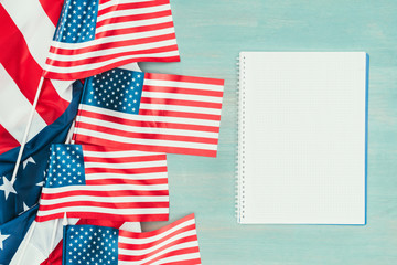 Obraz premium top view of arranged american flags and blank notebook on blue wooden tabletop, presidents day concept