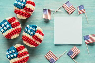 Obraz premium flat lay with arranged cupcakes and american flags on wooden tabletop, presidents day celebration concept
