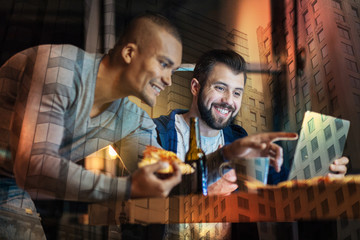 Amazing film. Emotional friendly young people feeling happy and laughing while watching a funny film on the screen of their modern laptop and drinking beer