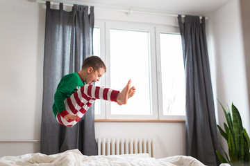 little boy jumping on bed in bedroom