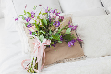 Bouquet of flowers on the pillow on the bed.