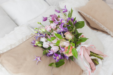 Delicate bouquet of flowers lies on the bed in the morning.