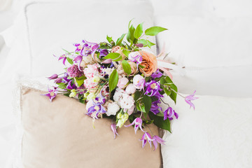 Bouquet of flowers lies on the pillow in the early morning, in gentle tones.