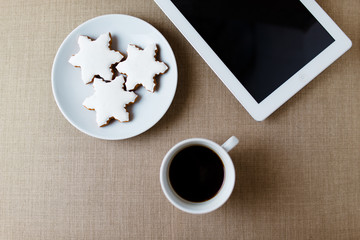 Morning cup of coffee on the shabby white desk with digital tablet with empty screen, candle, fresh cookie