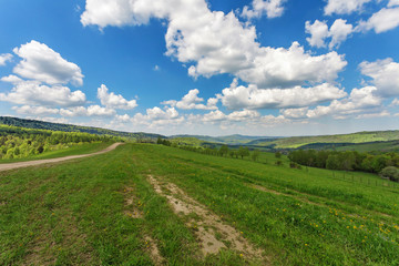 Blue cloudy sky over green hills and country road