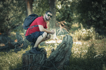 Happy young man with backpack hiking in the woods