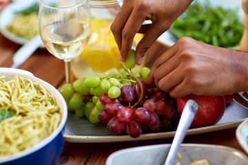 hands taking grape from plate with fruits