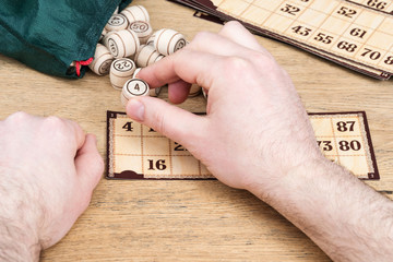 Fototapeta premium Male hands play in the lotto close the fallen figure on the card, close-up