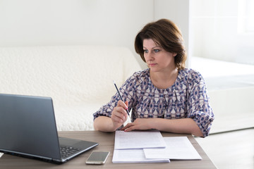 Woman working with documents looking at laptop