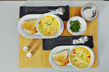 Served fish soup in a white plate, with toasts on a wooden tray, top view.