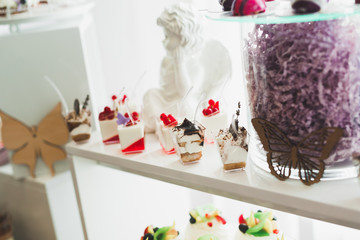 Delicious and tasty dessert table with cupcakes shots at reception closeup