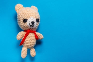 Hand made knitted wool bear on blue background