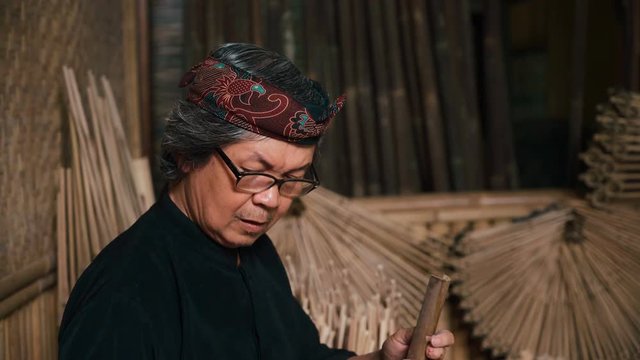 Old man tuning angklung by cutting it slightly