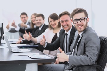 business team with thumbs up while sitting at his Desk