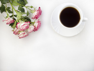 A cup of coffee on a white background and roses
