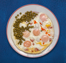 Breakfast scrambled eggs with peas and ham on a round white plate