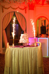 The wedding cake with fireworks stand on the table in restaurant