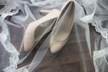 Beige bridal shoes are covered with a veil. Wedding details. 