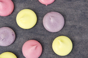 Pink, green and purple meringues on a grey background